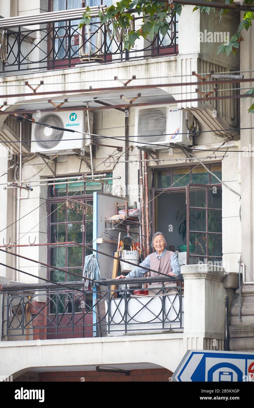 Donna cinese anziana sul balcone di casa a Shanghai Foto Stock