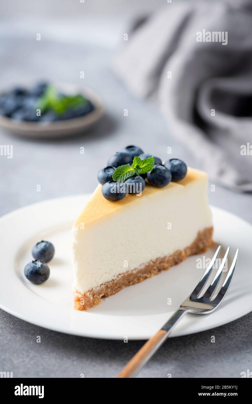 Cheesecake fetta con mirtilli freschi su piastra bianca, orientamento verticale Foto Stock