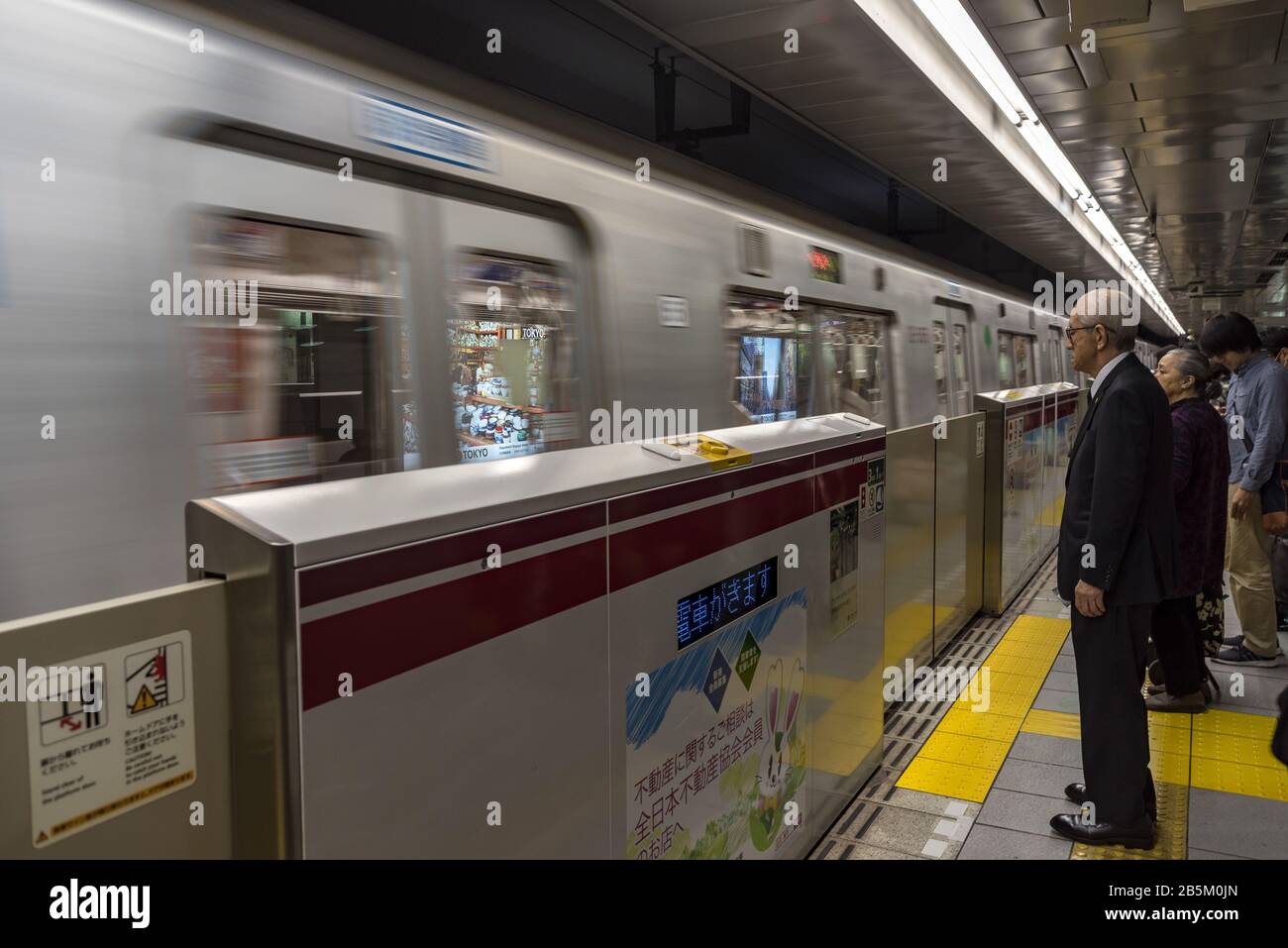 I pendolari attendono l'arrivo del treno della metropolitana di Tokyo, la stazione di Shinjuku, Giappone Foto Stock