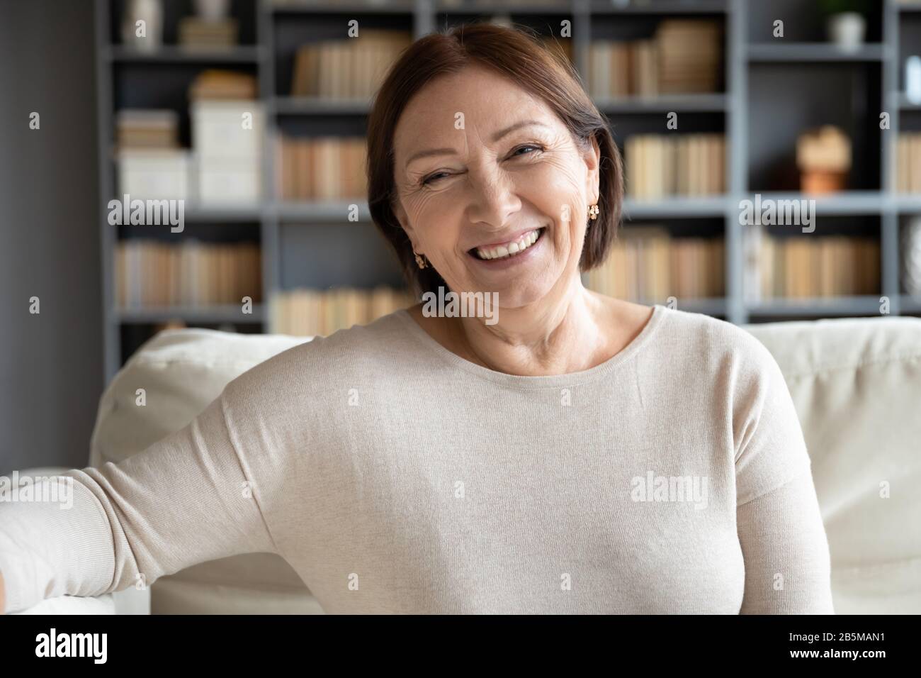 Sorridente piacevole madre 50s anziana che guarda la macchina fotografica. Foto Stock