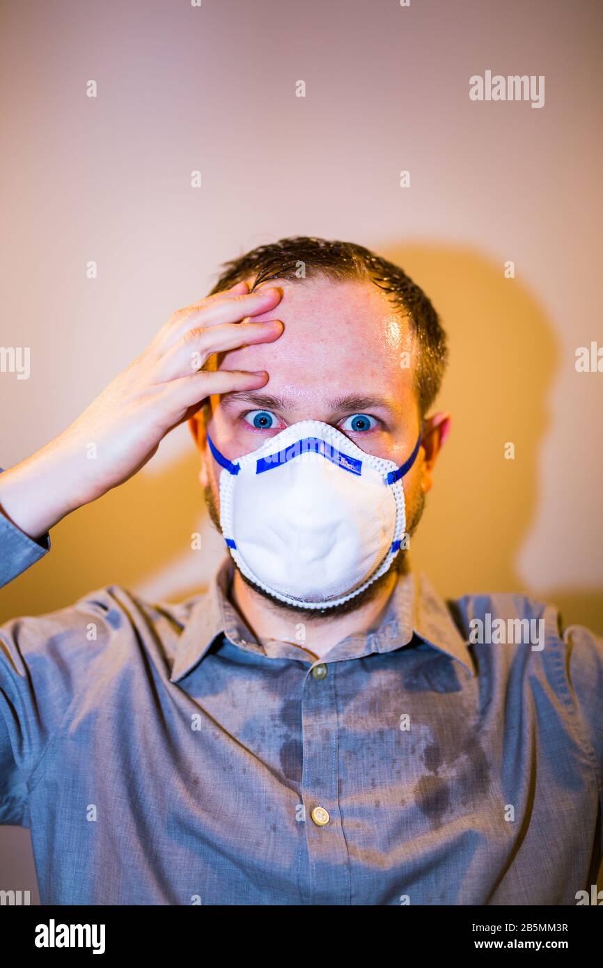 Uomo con Coronavirus reale COVID-19 sintomi di malattia indossa una maschera protettiva Foto Stock