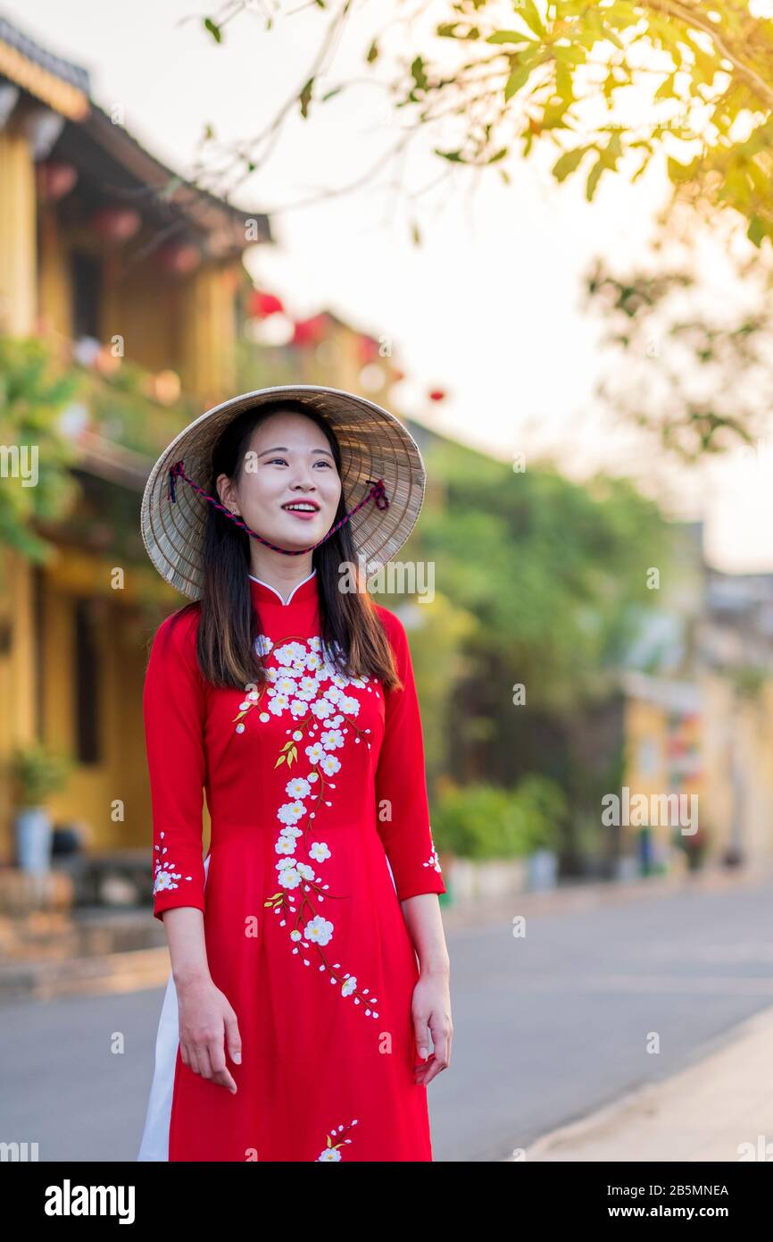 Una giovane donna vietnamita indossa un tradizionale abito Ao dai nelle strade della vecchia Hoi An Foto Stock