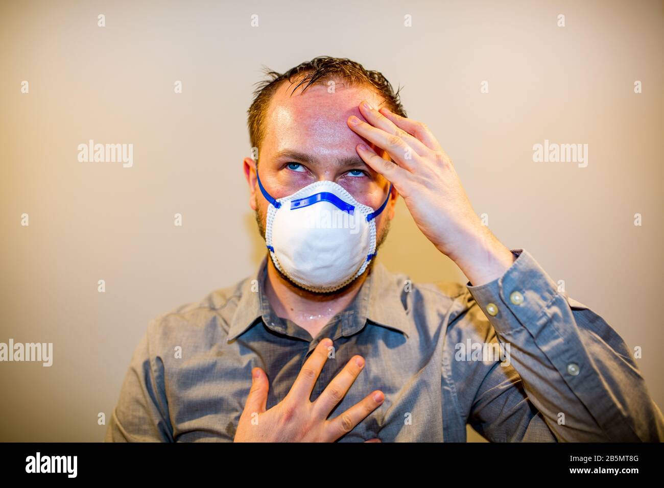 Uomo con Coronavirus reale COVID-19 sintomi di malattia indossa una maschera protettiva Foto Stock