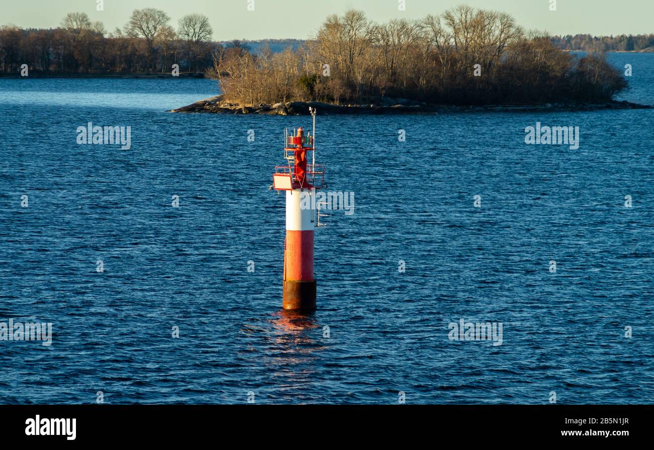 Faro nello stretto tra le isole dell'arcipelago di Stoccolma, illuminato dai raggi del sole, al mattino presto. Foto Stock
