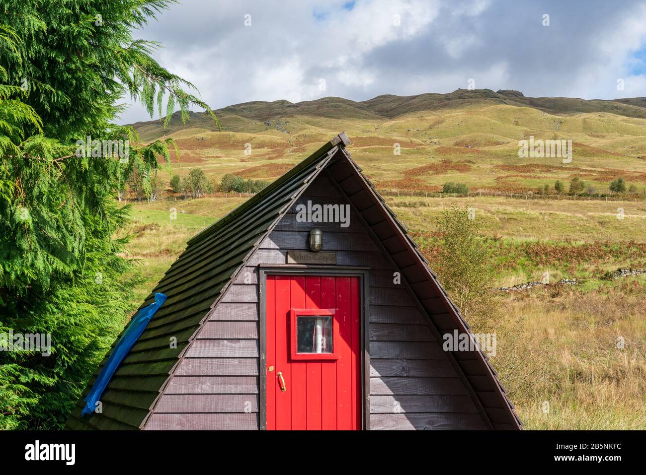 Una capanna da campeggio con una porta rossa lungo il sentiero escursionistico, la West Highland Way Foto Stock