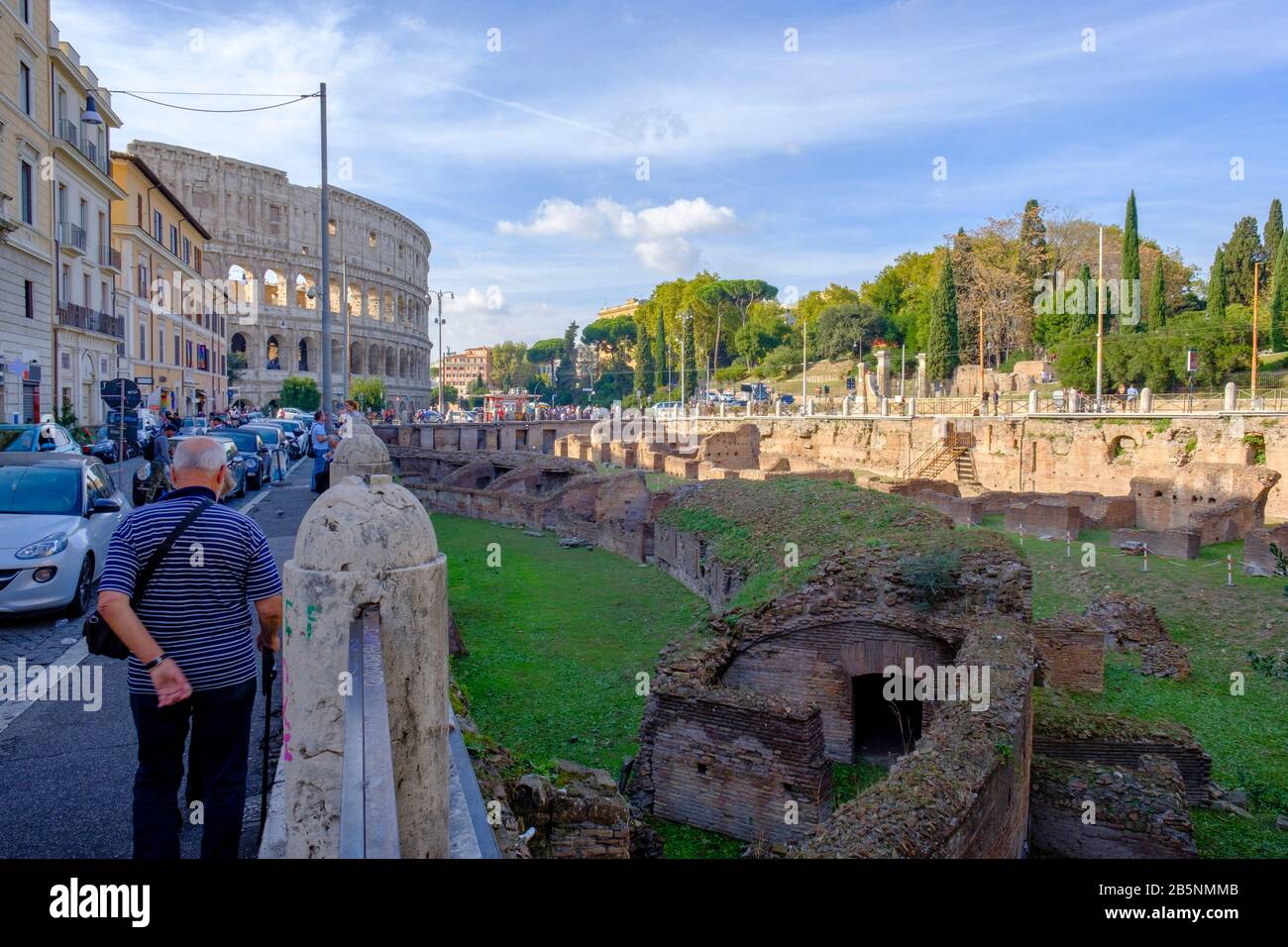 Edifici dell'antica Roma, vista sulla strada delle rovine di Ludo Magnus, Scuola di formazione dei grandi gladiatori, con Colosseo romano sullo sfondo, Roma, Italia. Foto Stock