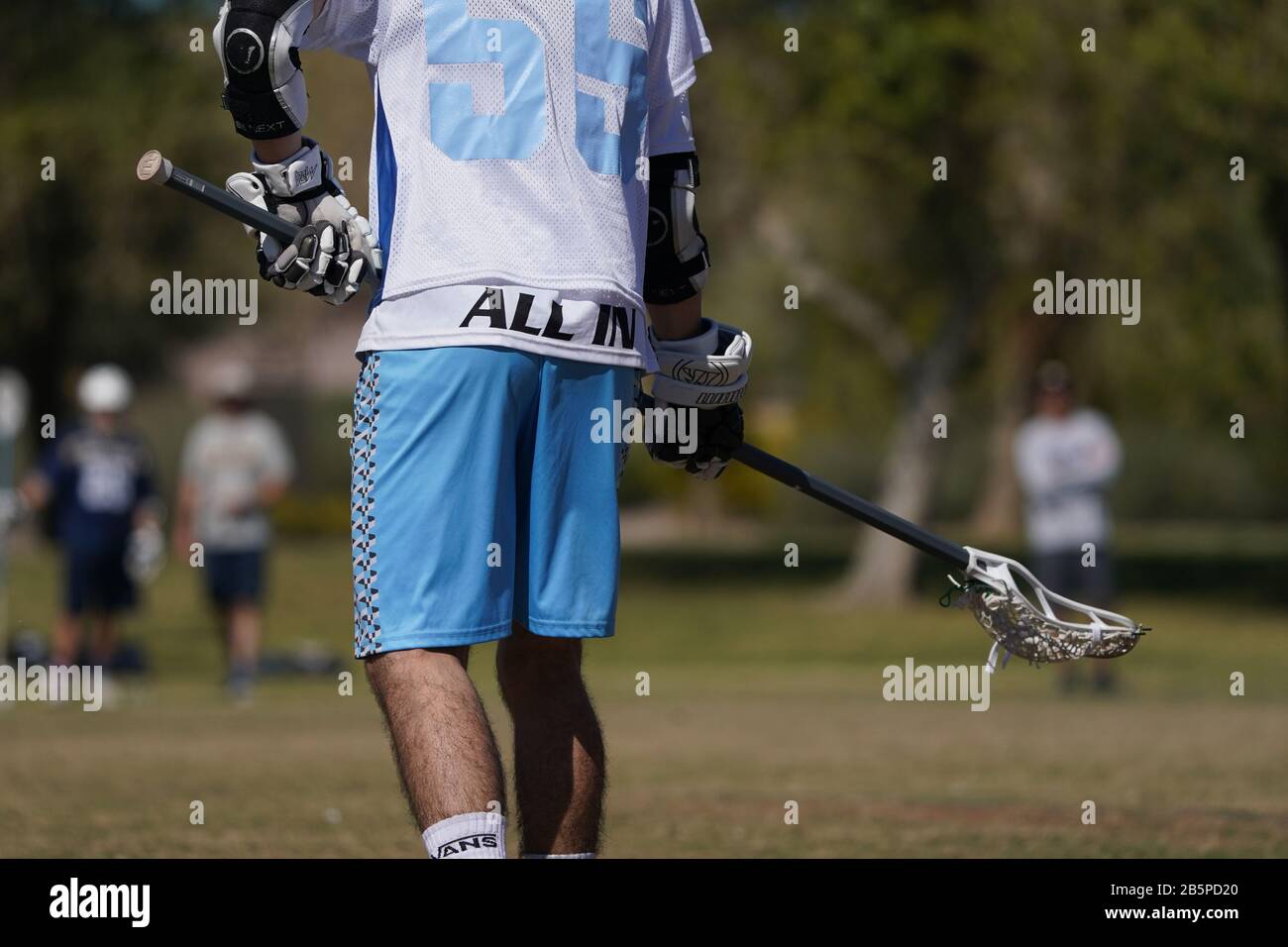 Un colpo stretto di un giocatore di lacrosse che tiene il suo bastone pronto per l'azione. Foto Stock