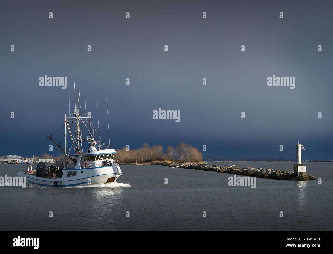 Pesca Mare Steveston Harbor. Una barca sulla senna viaggia fuori dall'entrata del Porto di Steveston nello stretto della Georgia. Nuvole tempesta apparire sullo sfondo Foto Stock