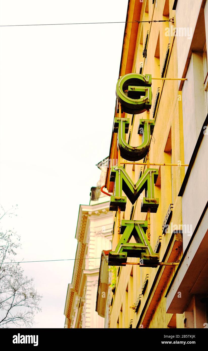Insegna al neon vintage vista alla luce del giorno dal basso, tipografia russa socialrealista e modernista, audaci lettere di serif in verde contro una facciata gialla Praga Foto Stock
