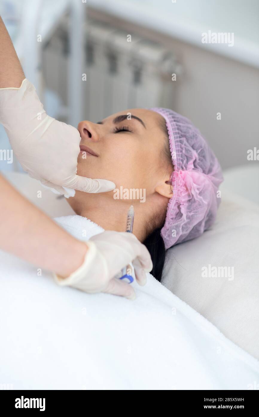 Donna che ha iniezione nel collo mentre ha procedure anti-invecchiamento Foto Stock