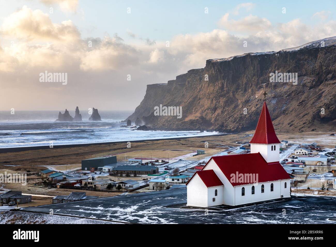 Le incredibili formazioni rocciose di basalto nero Reynisdrangar, altrimenti conosciute come le dita dei piedi troll, e la pittoresca chiesa coperta rossa Vik i Myrdal, Vik, Ic Foto Stock
