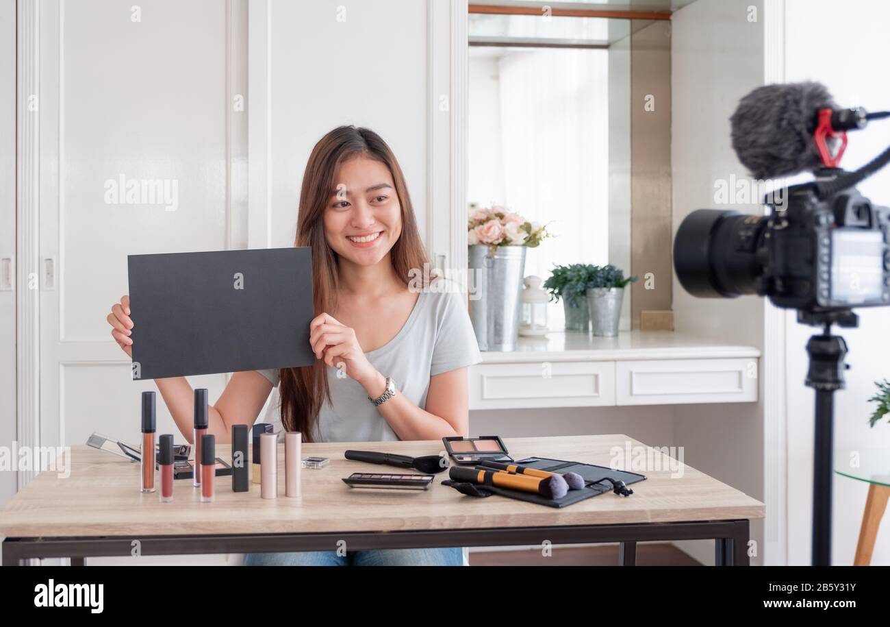 Asian giovane femmina blogger giveaway dono ventilatore a seguito di canale durante la registrazione vlog video con cosmetici per il trucco a home online influencer concetto.live Foto Stock