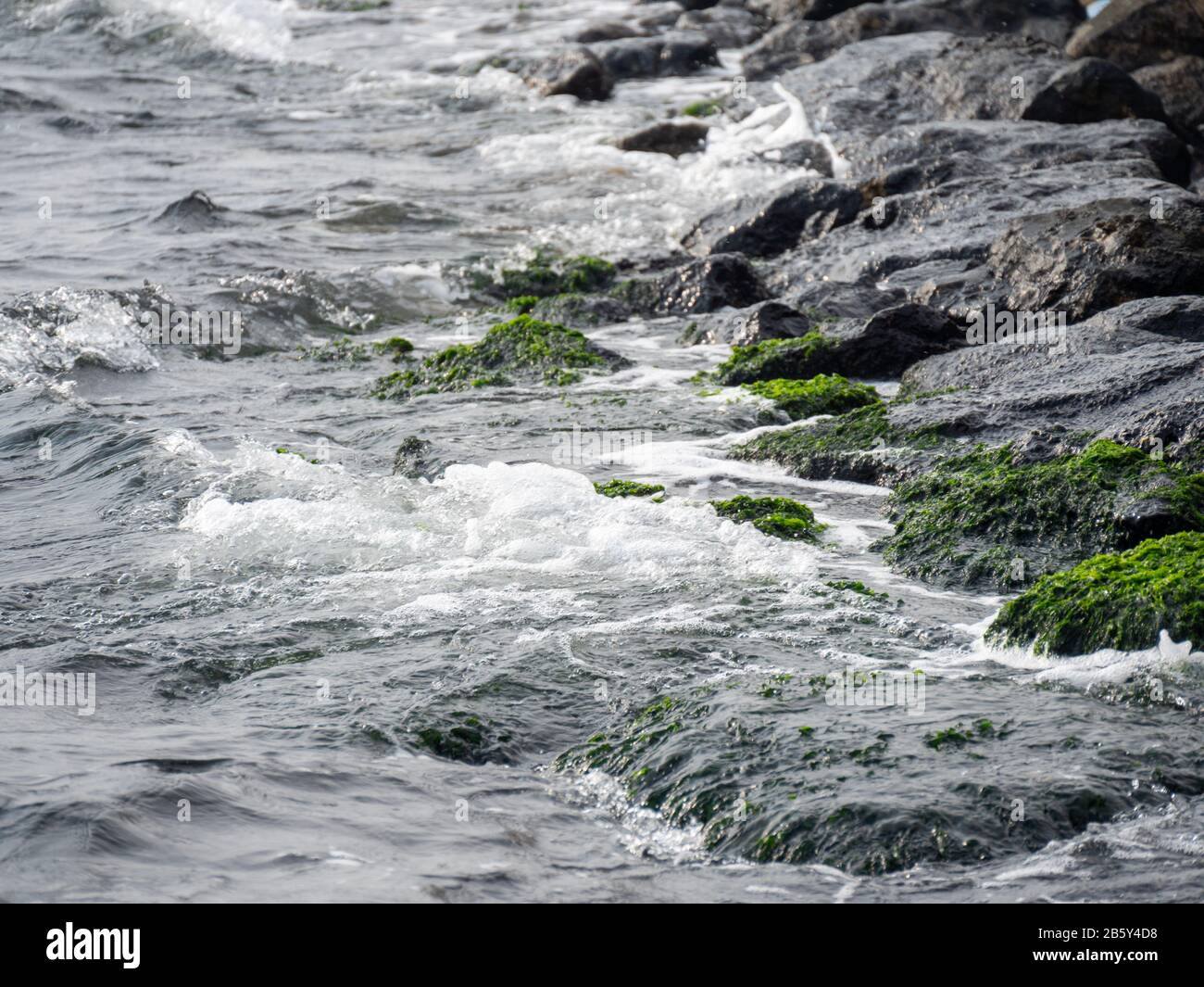 Le onde colpiscono le rocce e spruzzi d'acqua di mare. Fuoco selettivo. Foto Stock