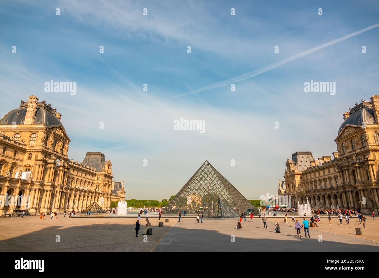 Francia. Estate giornata di sole a Parigi. Cortile del Museo del Louvre con fontane e cielo blu. Piramide di vetro e turisti Foto Stock