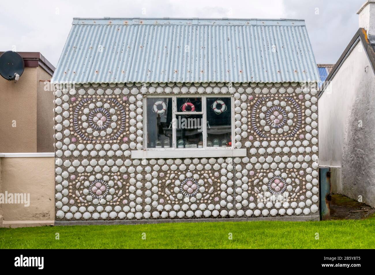 Un piccolo edificio coperto di conchiglie marine a Hamnavoe sull'isola di Burra occidentale al largo della terraferma Shetland. Foto Stock