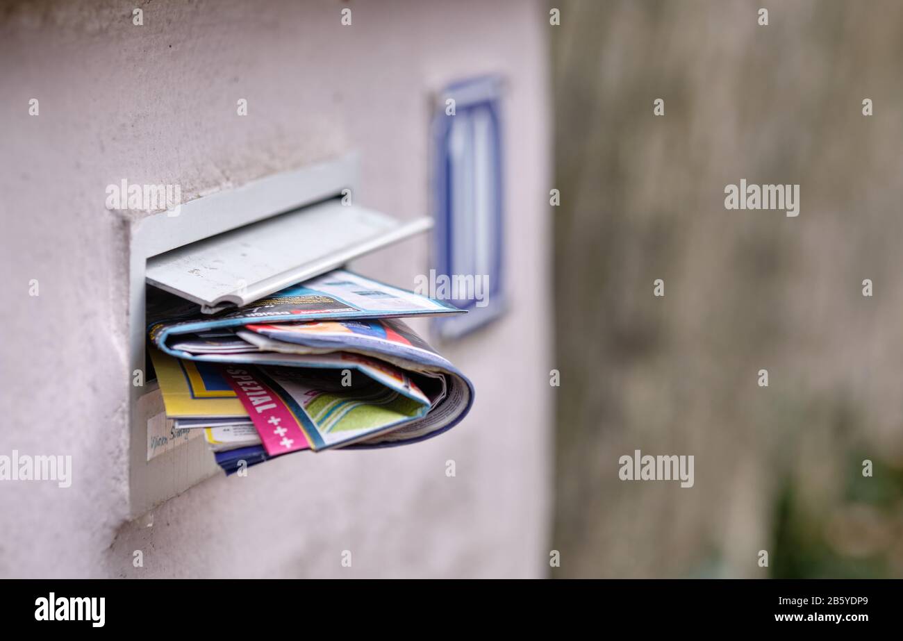 Norimberga, Germania - 16 febbraio 2020: Una casella postale in un muro di giardino di una casa trabocchita di giornali pubblicitari gratuiti Foto Stock