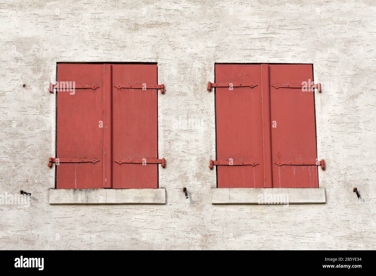 Primo piano di due finestre di un vecchio fienile restaurato con le persiane in legno rosso chiuso. Visto in Germania nel mese di febbraio Foto Stock