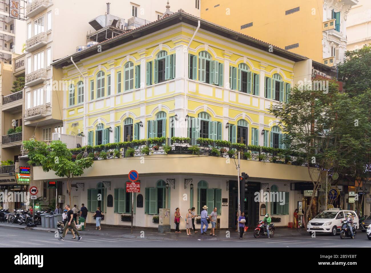 Edificio giallo dell'era coloniale francese con persiane verdi su un angolo di strada a Ho Chi Minh City (Saigon), Vietnam. Foto Stock