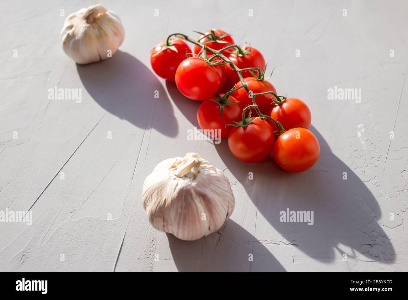 Pomodori freschi e aglio su sfondo grigio. Ingredienti per ketchup. Spazio di copia. Foto Stock