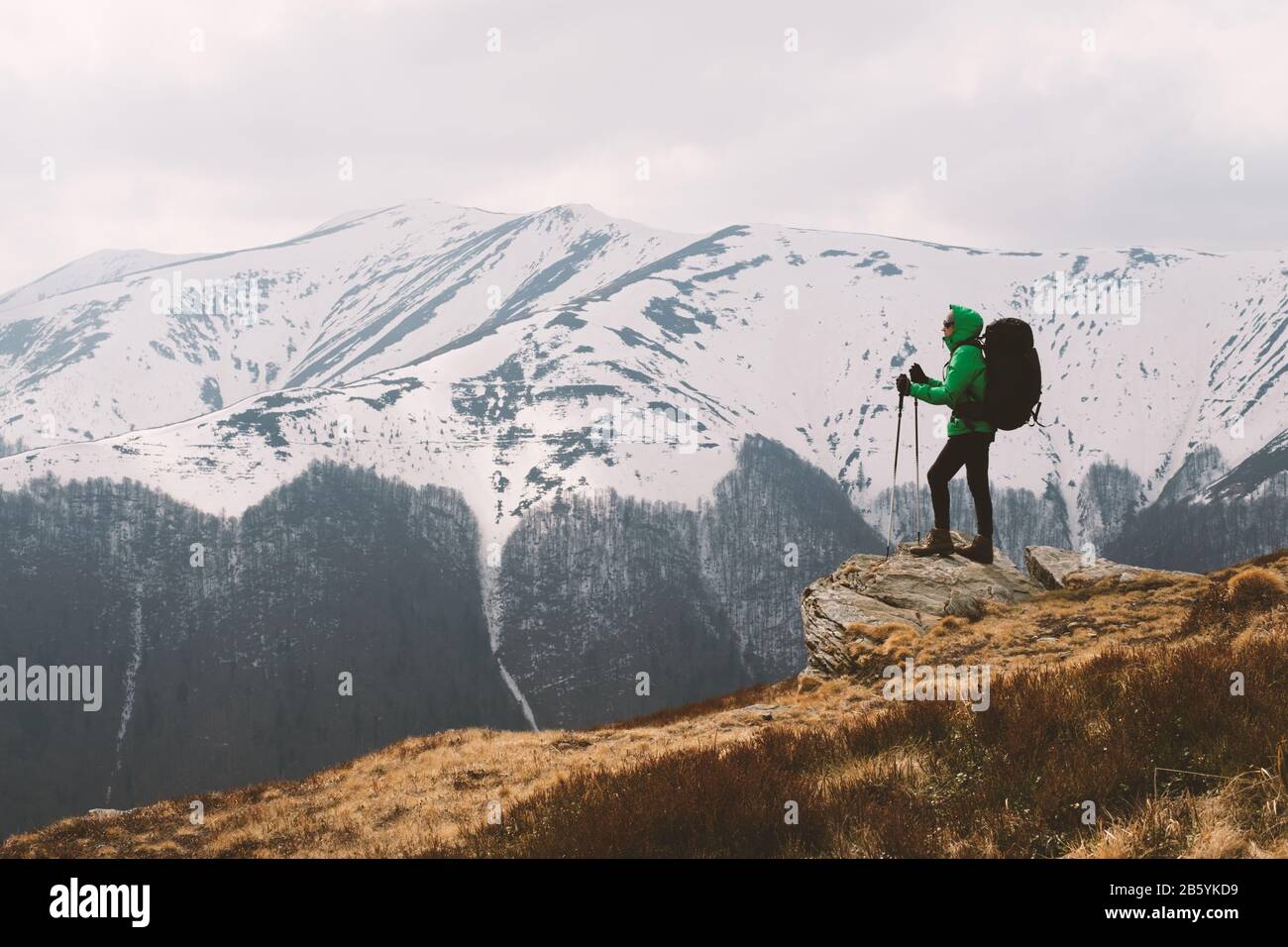 Un paesaggio fantastico con montagne innevate e gamma escursionista con zaino su un primo piano Foto Stock