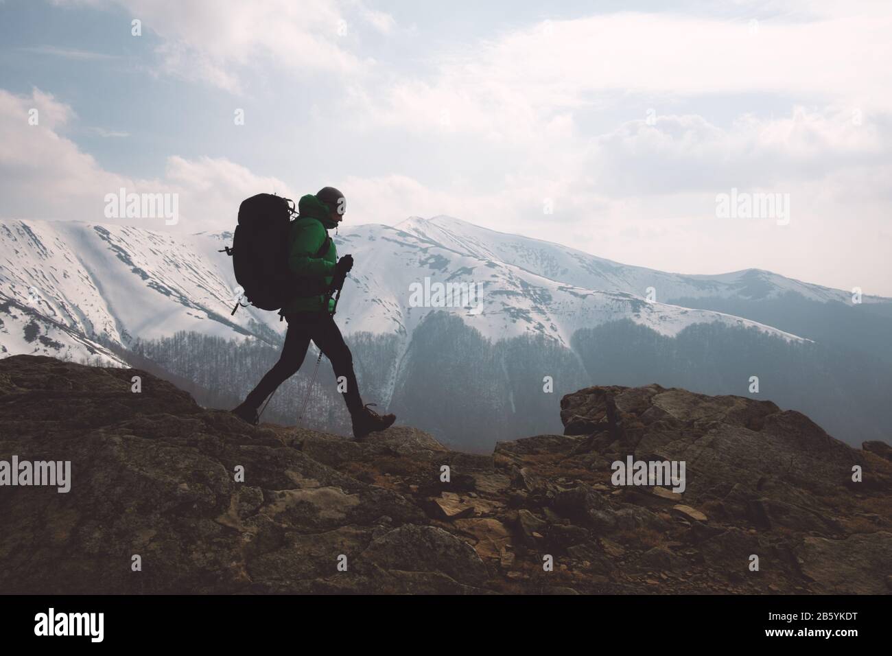 Un paesaggio fantastico con montagne innevate e gamma escursionista con zaino su un primo piano Foto Stock