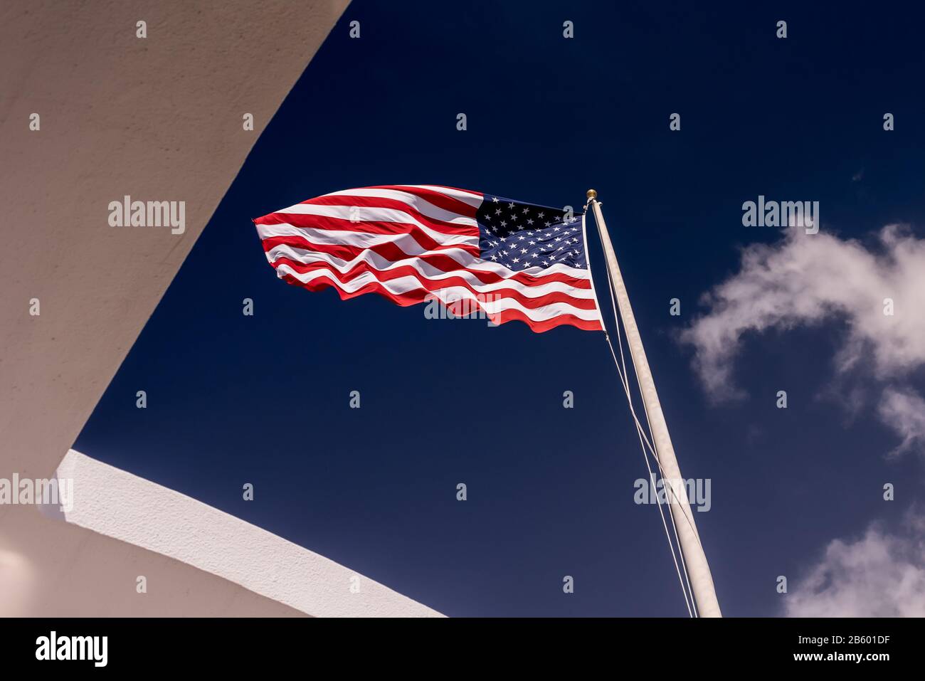 Bandiera americana che soffia nel vento sopra l'USS Arizona Memorial a Pearl Harbour, Hawaii Foto Stock