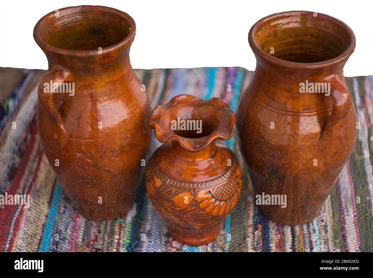vaso tradizionale in ceramica seduto su un colorato tappeto vecchio con sfondo bianco Foto Stock
