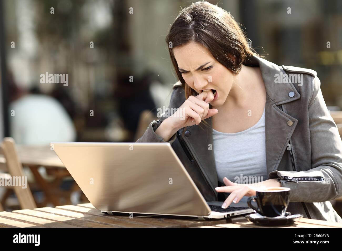 Ragazza arrabbiata premendo il pulsante frustrato usando il suo portatile su una terrazza della caffetteria Foto Stock