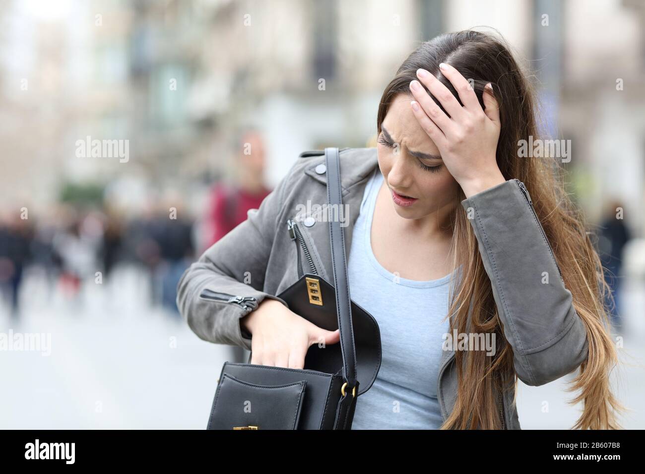 Vista frontale di una donna preoccupata che guarda preoccupato all'interno della sua borsa su una strada della città Foto Stock