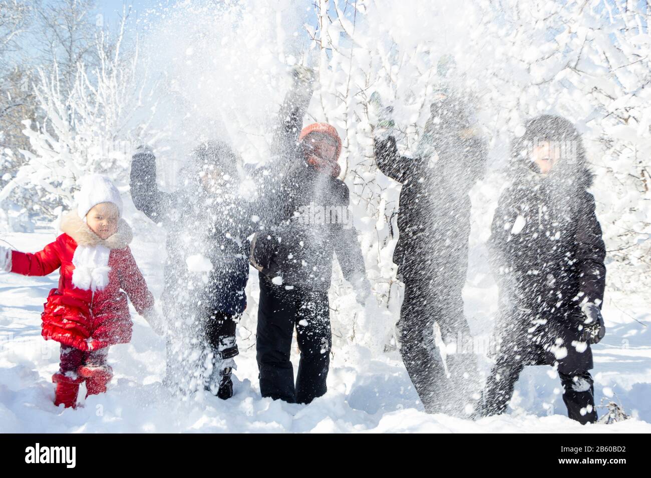 Un gruppo di bambini getta la neve e godersi i giochi invernali in aria fresca e gelida. Alberi coperti di neve dietro di loro. Meravigliosa vacanza invernale. Sano Foto Stock