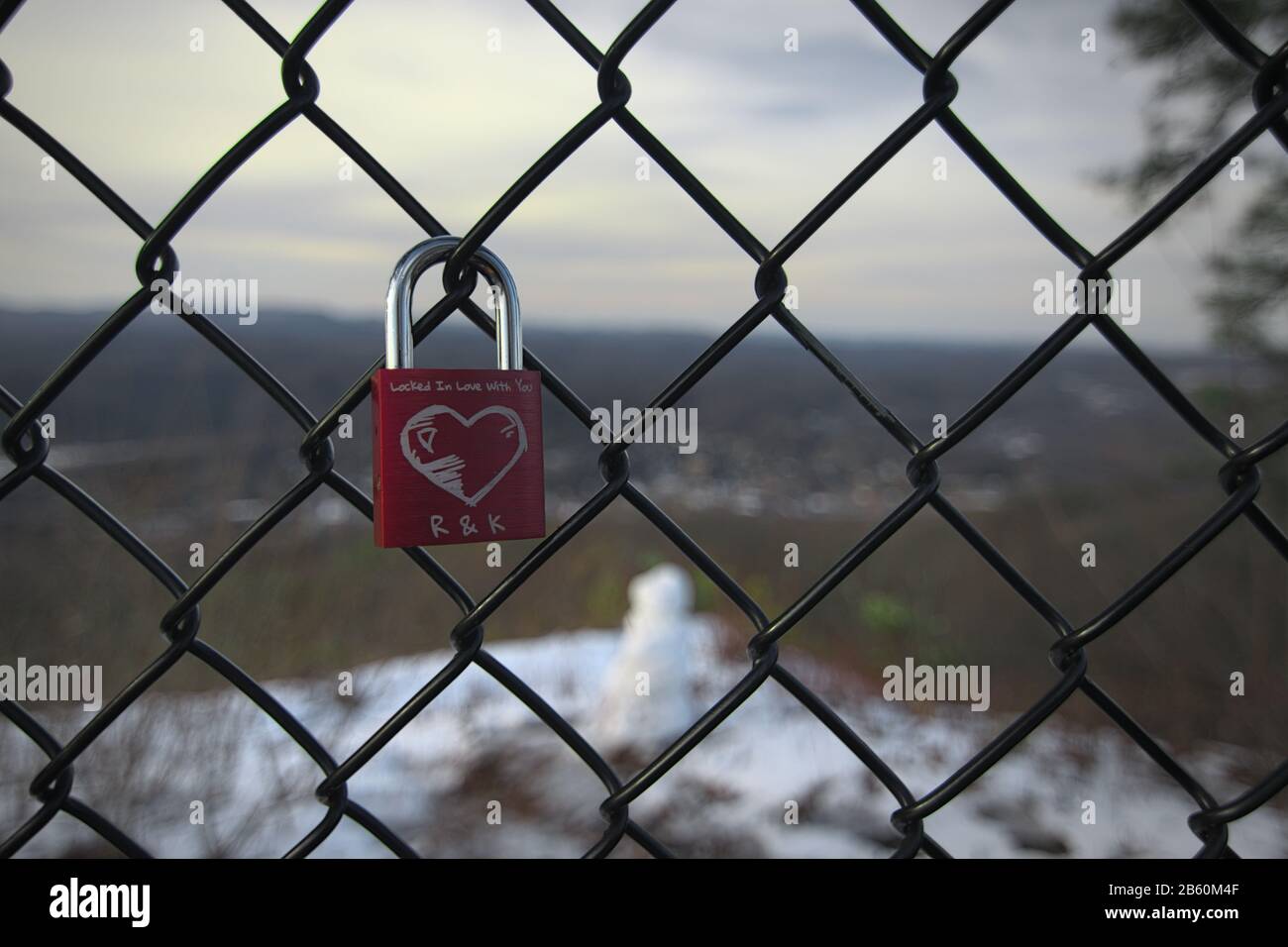Un lucchetto singolo con un cuore graffiato scolpito in esso con le iniziali e la citazione d'amore allegata ad una recinzione che circonda Flag Rock a Norton Virgin Foto Stock