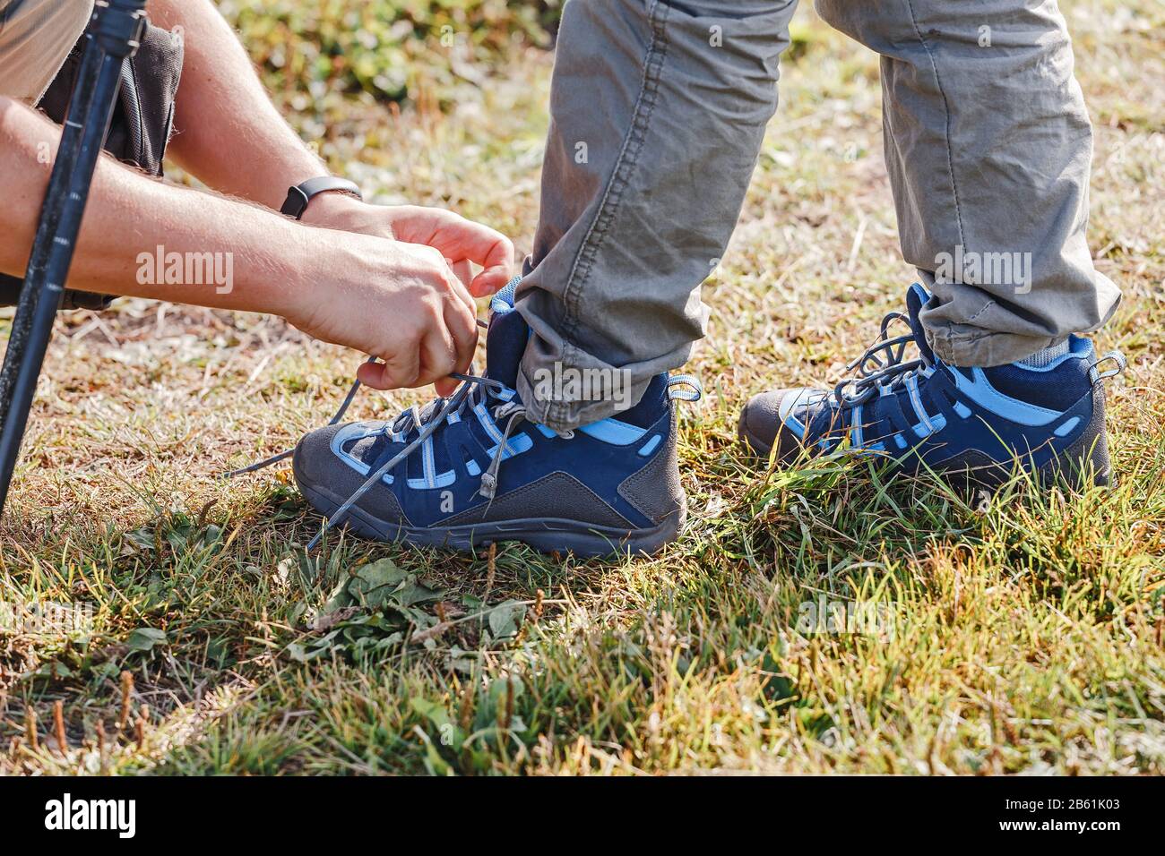 Vista ravvicinata del padre che legava lo shoelace per il figlio durante le escursioni nella foresta Foto Stock