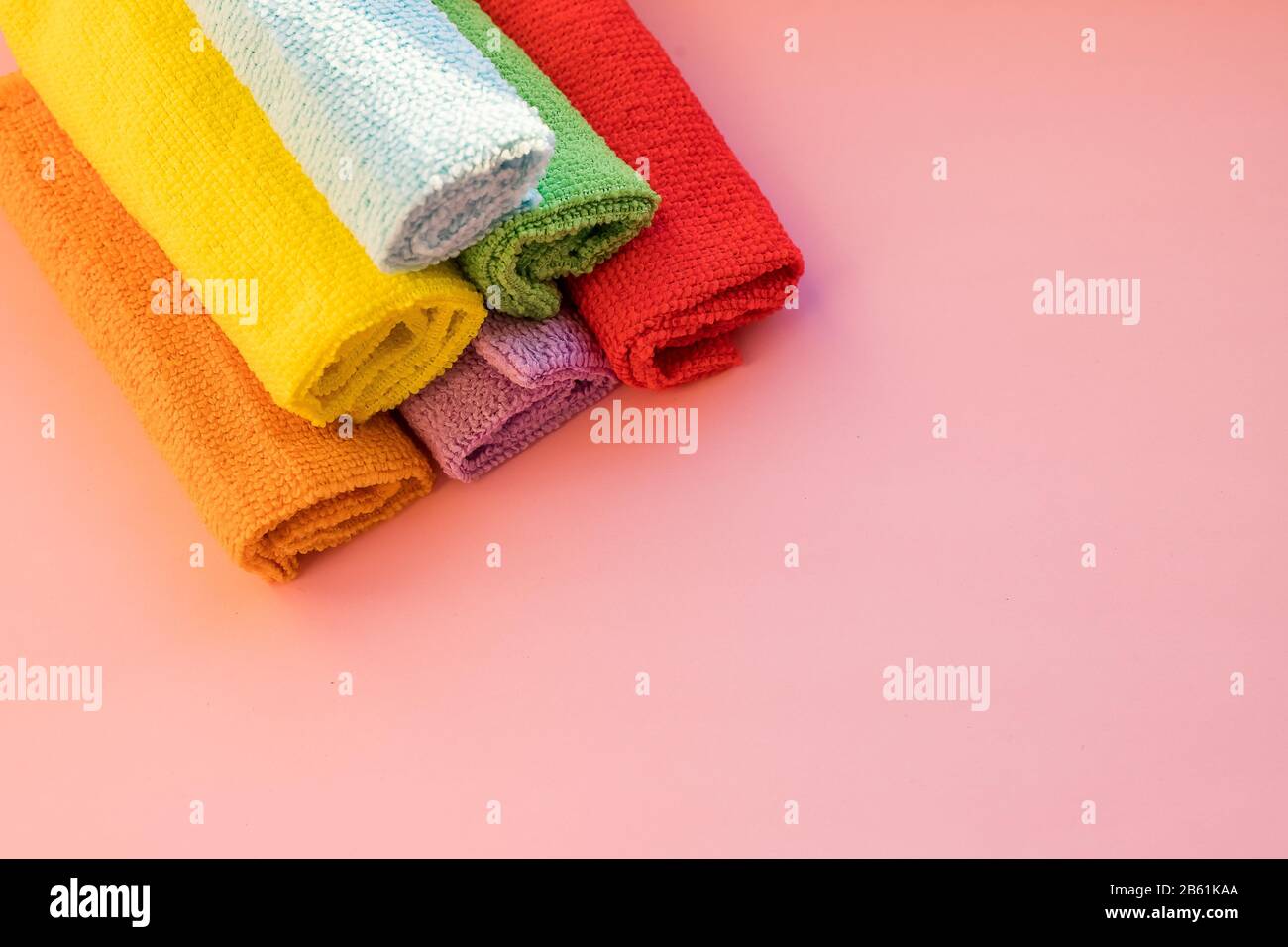panni in microfibra colorati impilati su sfondo rosa. Panni colorati e asciutti in microfibra per la pulizia di diverse superfici in cucina, bagno Foto Stock