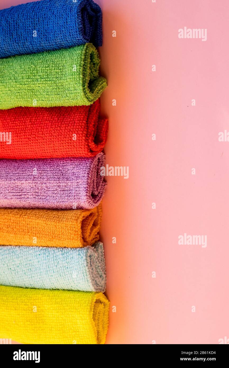 panni in microfibra colorati impilati su sfondo rosa. Panni colorati e asciutti in microfibra per la pulizia di diverse superfici in cucina, bagno Foto Stock