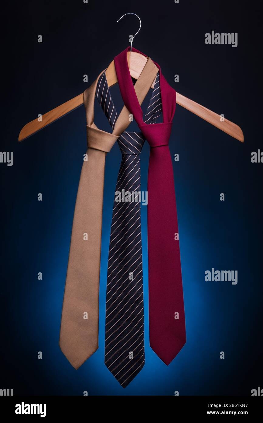Cravatte alla moda da uomo su un appendiabiti. Su sfondo blu. Foto Stock