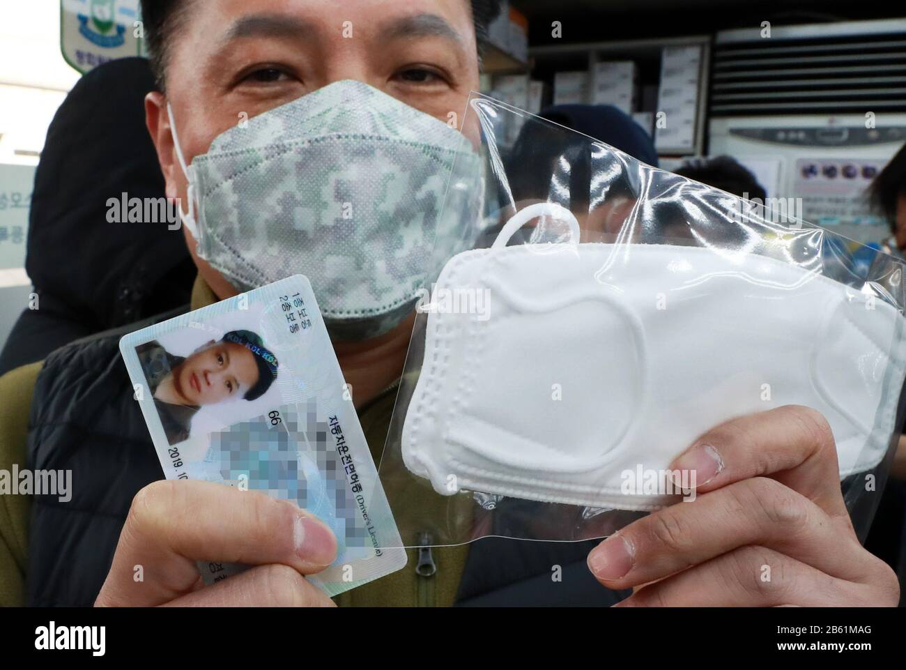 (200309) -- SEOUL, 9 marzo 2020 (Xinhua) -- un uomo mostra una maschera facciale appena acquistata e la carta d'identità richiesta durante l'acquisto, a Seoul, Corea del Sud, 9 marzo 2020. La Corea del Sud ha confermato altri 96 casi del COVID-19 lunedì, portando il numero totale di infezioni a 7.478. (NEWSIS/consegna via Xinhua) Foto Stock