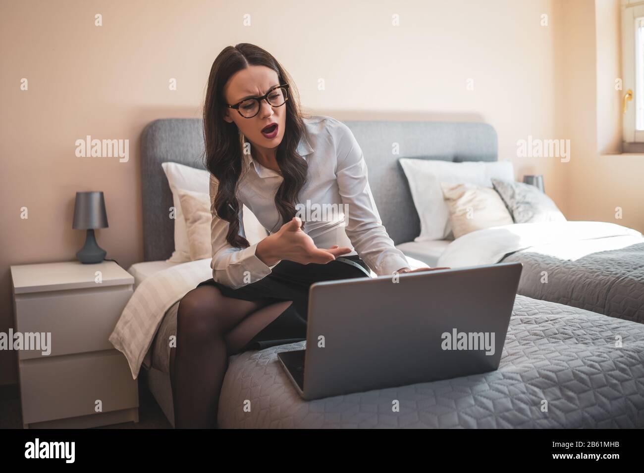 Donna d'affari in viaggio d'affari seduto in camera d'albergo e lavorando su un computer portatile. Foto Stock