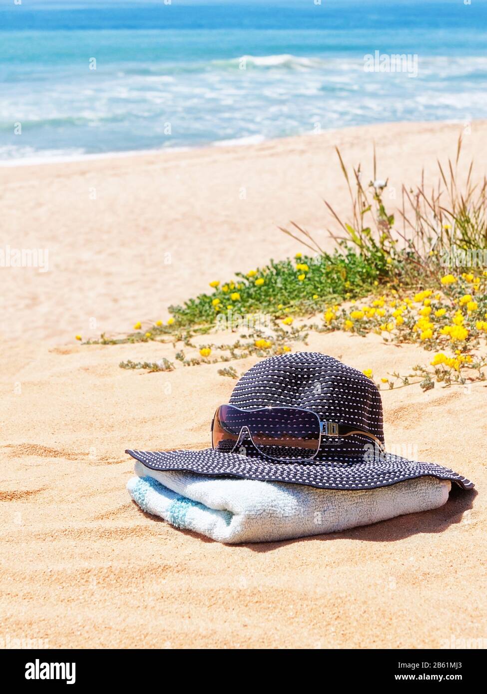 Cappello Panama da donna con occhiali da sole su un asciugamano sulla spiaggia in estate. Foto Stock