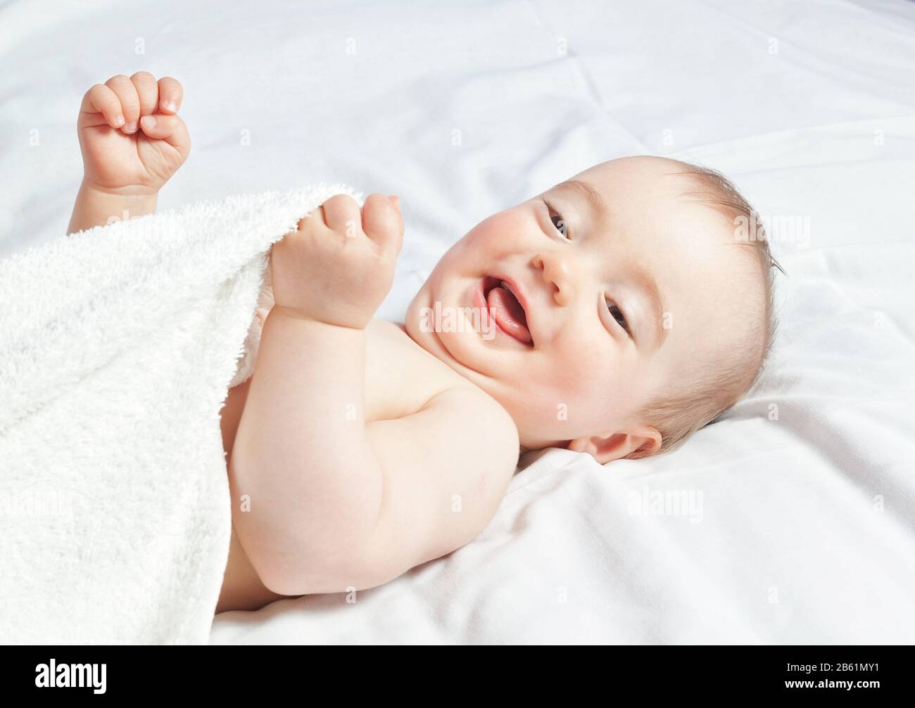 Baby girl senza pepore sdraiato sorridendo. Primo piano. Foto Stock