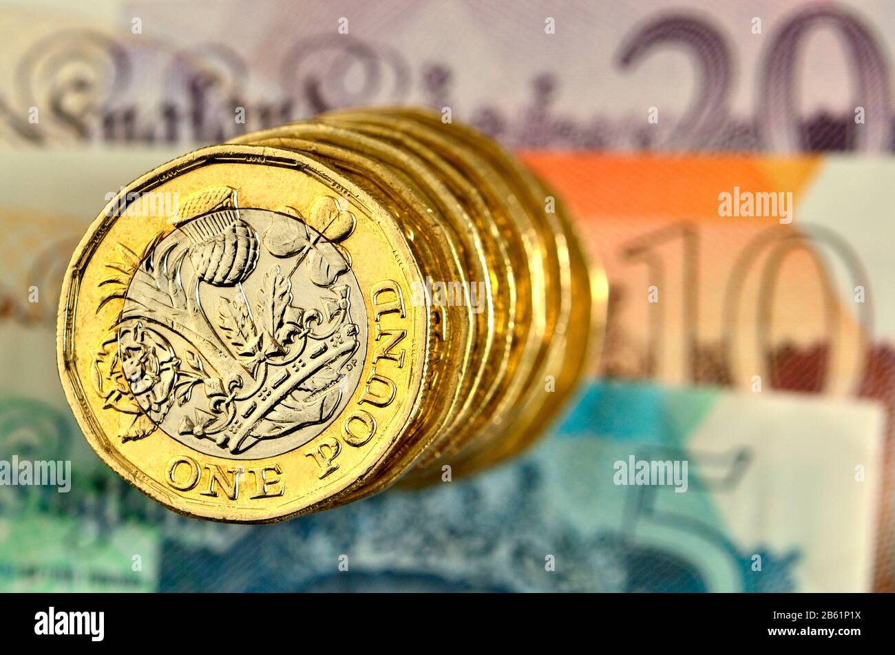 Pile di monete britanniche in sterline su banconote Foto Stock