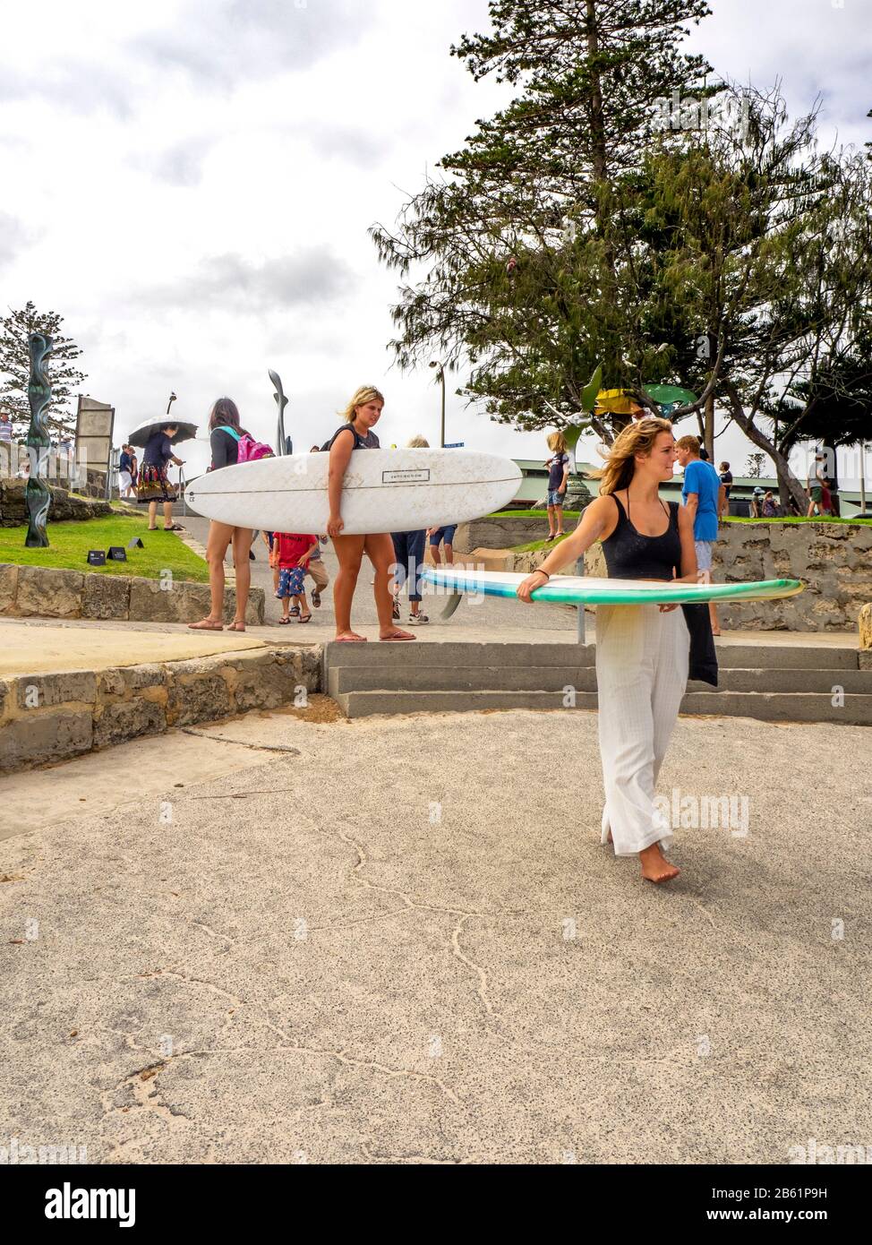 Due donne caucasiche trasportano tavole da surf alla spiaggia a Cottesloe Beach Perth WA Australia Foto Stock