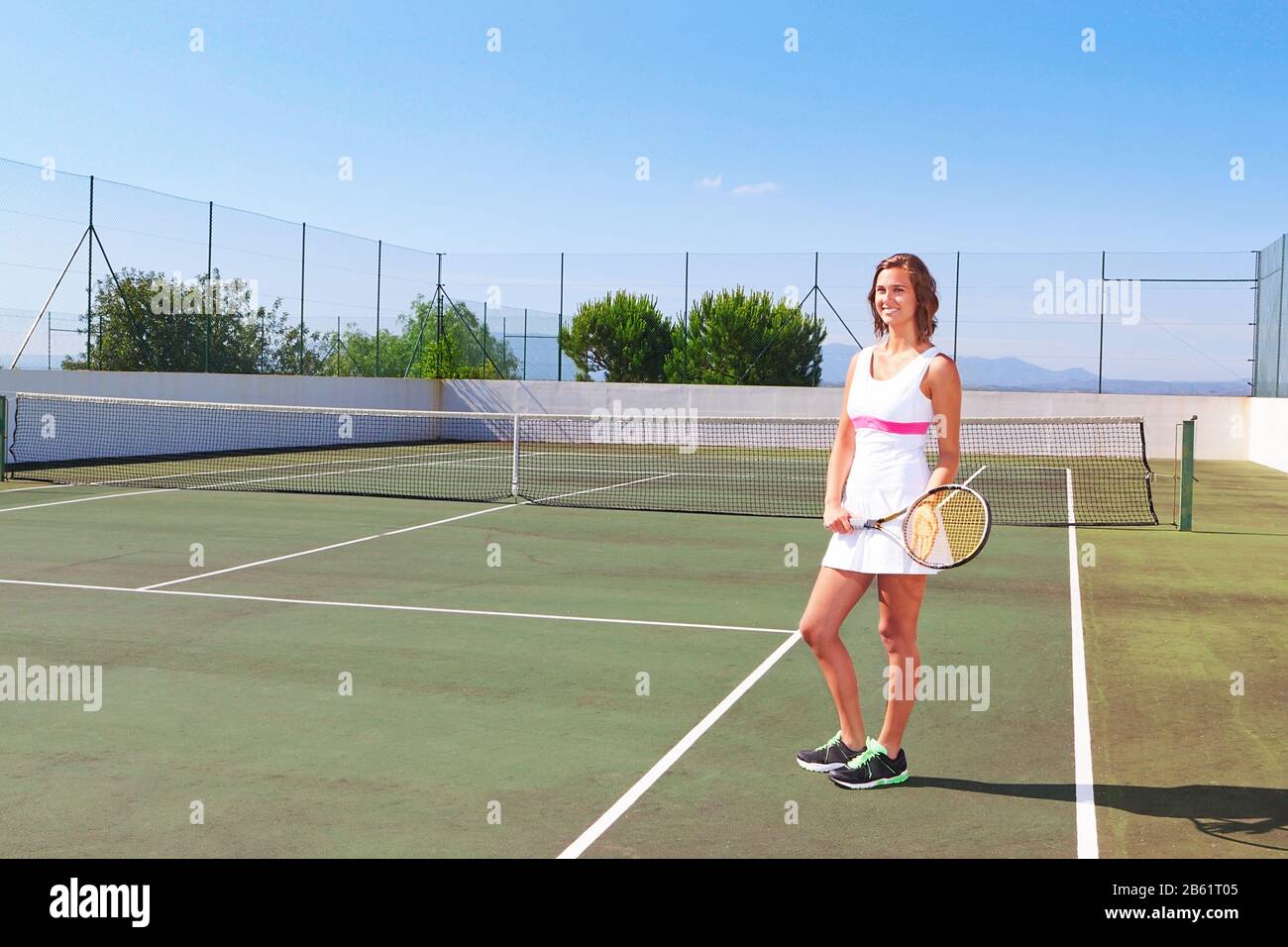 Bella ragazza giovane con una racchetta da tennis che posa per la stampa. Sul campo da tennis. Foto Stock