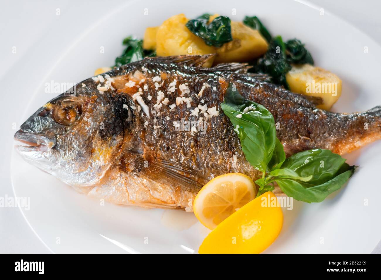 Pesce dorato arrosto con patate al forno. Foto Stock
