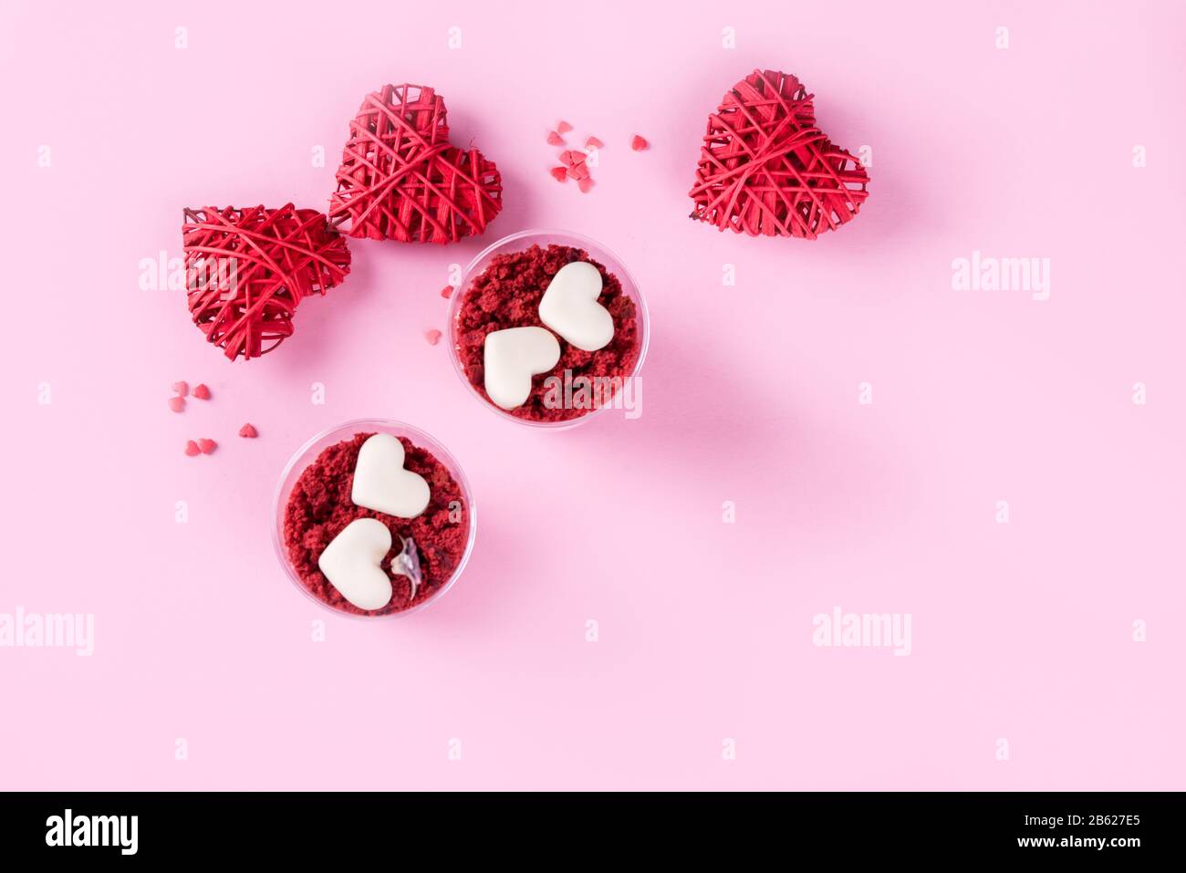 Delizioso e bellissimo dessert, velluto rosso in tazze. Cuori di cioccolato bianco. San Valentino, un luogo per scrivere su uno sfondo rosa. Foto Stock