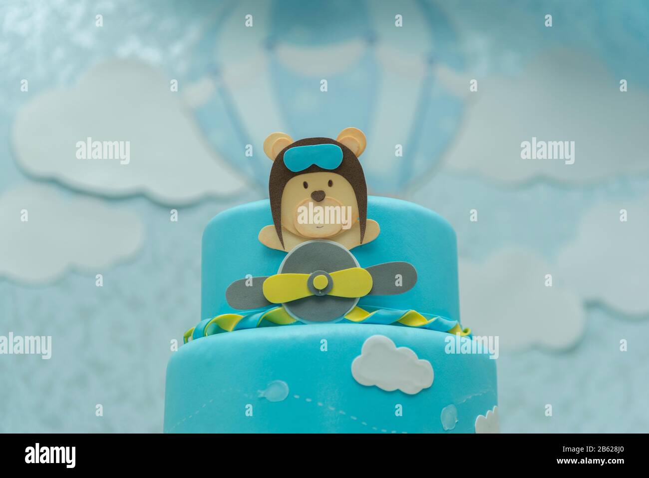 Primo piano di torta blu decorata con carino orso aviatore, aereo e nuvole. Foto Stock