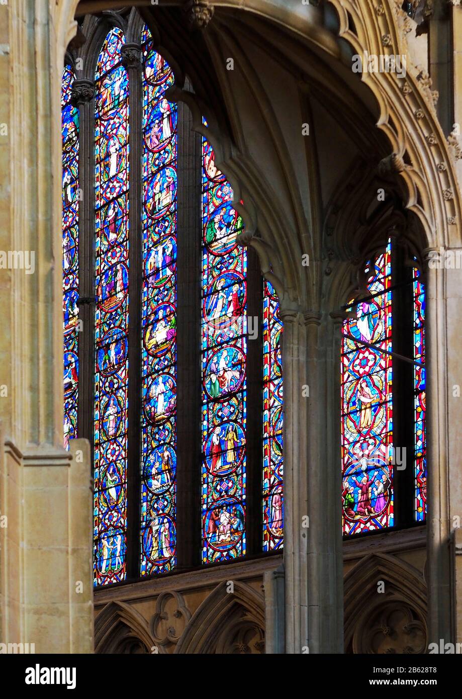 La bella vetrata della finestra est della Cattedrale di Lincoln visto attraverso la pietra scolpita di una cappella laterale. Foto Stock