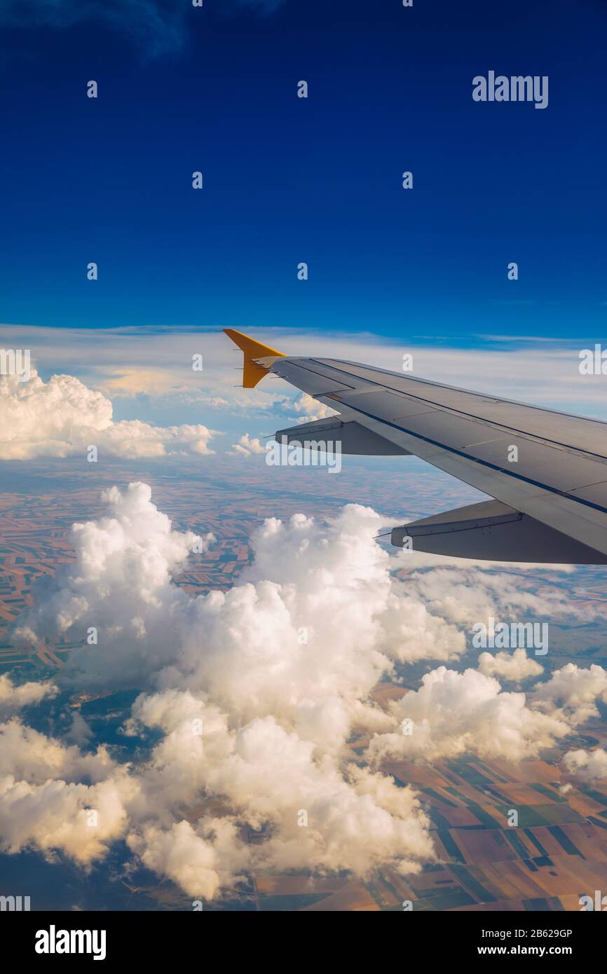 Vista di un'ala di aeroplano che vola sopra le nuvole ad alta altitudine sotto un cielo blu dall'alzavetro passeggero. In volo sopra l'Europa. Vista di je Foto Stock