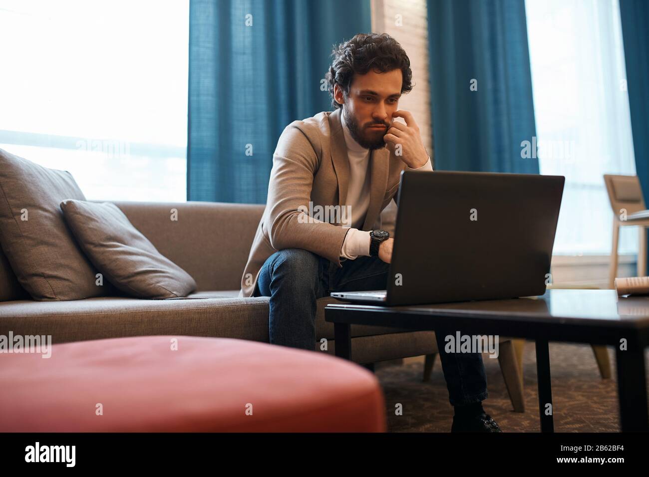 giovane uomo con bearded concentrato sull'uso del laptop, primo piano foto. giovane ragazzo guadagnare soldi online, guardare film, film Foto Stock