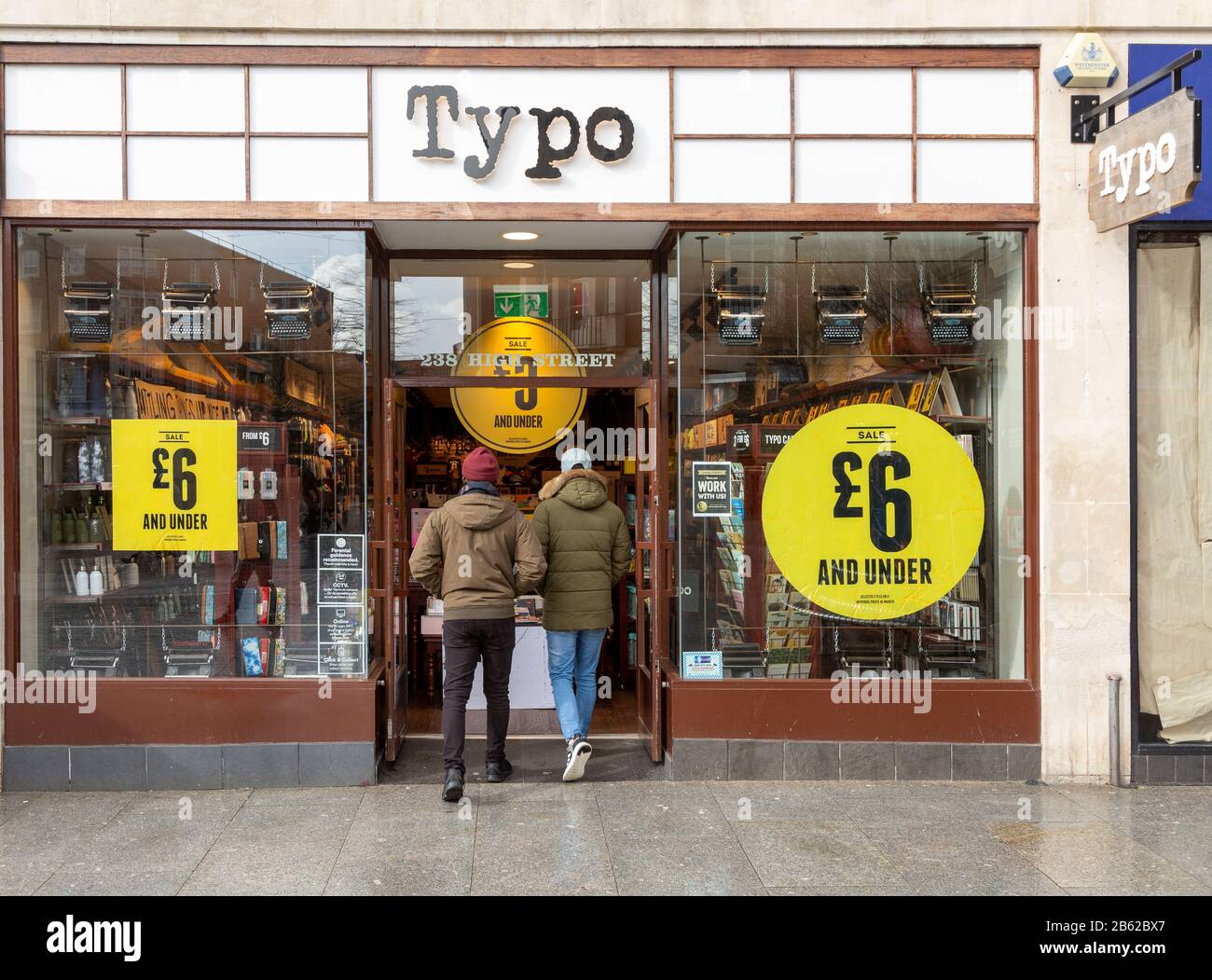 Vendita a Typo negozio nel centro della città High Street negozio, Exeter, Devon, Inghilterra, Regno Unito - due persone entrando porta Foto Stock