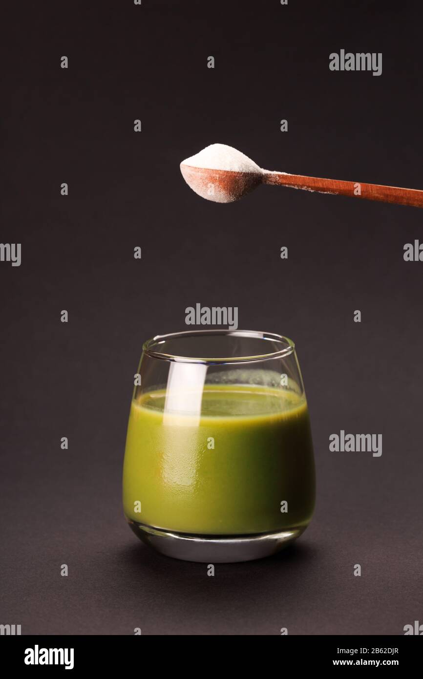 Succo verde con un cucchiaio di proteine o di collagene. Integratore alimentare concept Foto Stock